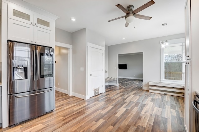 kitchen featuring white cabinetry, baseboards, light wood-style floors, stainless steel fridge, and glass insert cabinets