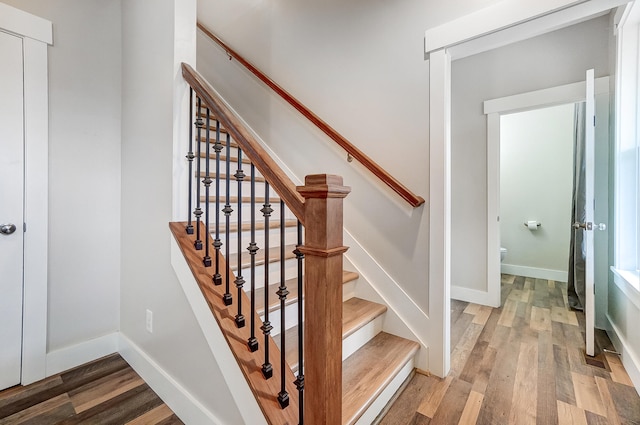 staircase featuring wood finished floors and baseboards