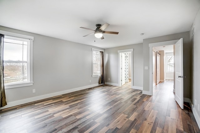 interior space featuring a ceiling fan, visible vents, baseboards, and wood finished floors