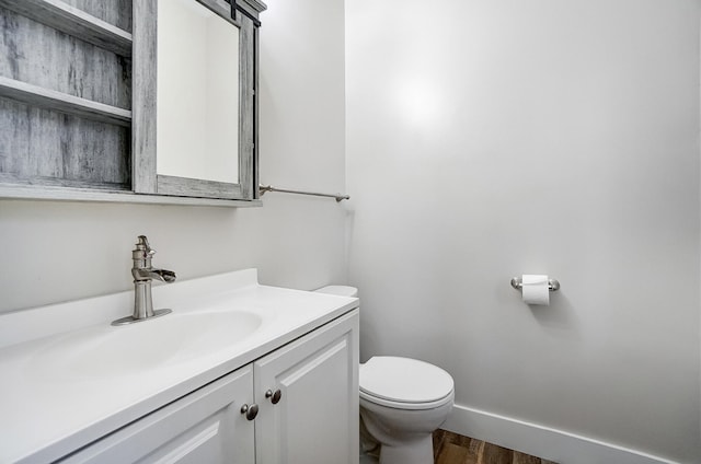 half bathroom featuring toilet, baseboards, wood finished floors, and vanity