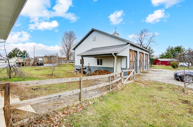 view of home's exterior with a chimney, a lawn, metal roof, fence, and an outdoor structure