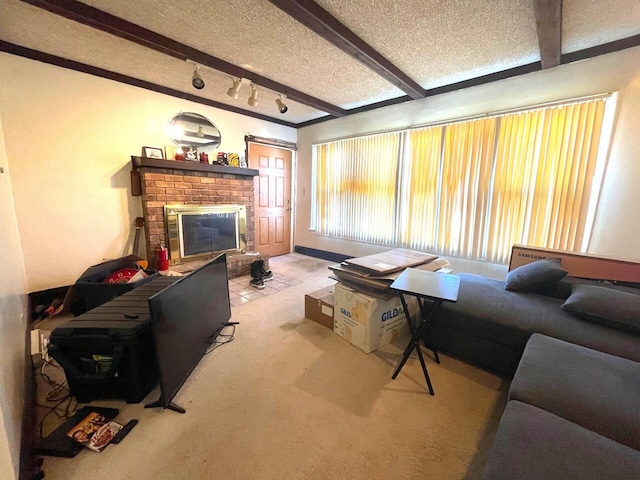 living room featuring a textured ceiling, carpet floors, a brick fireplace, beamed ceiling, and rail lighting