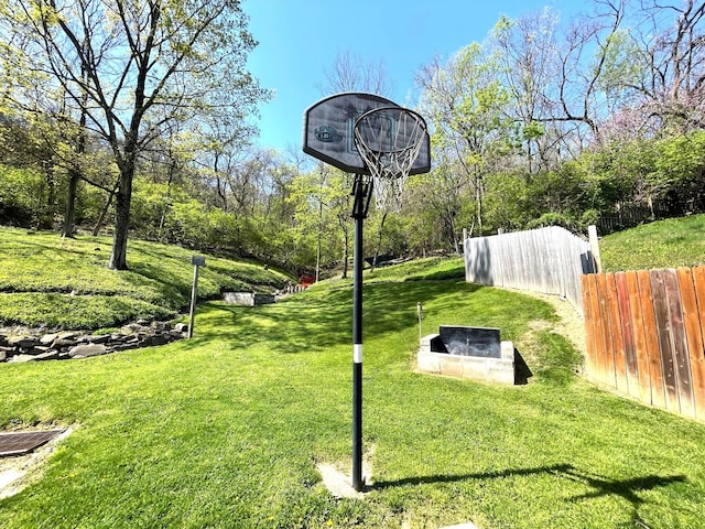 view of basketball court featuring a yard and fence
