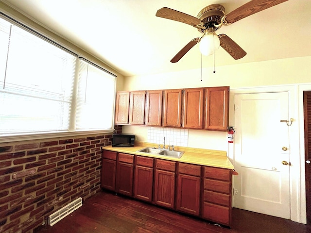 kitchen featuring light countertops, visible vents, a sink, dark wood-type flooring, and brick wall