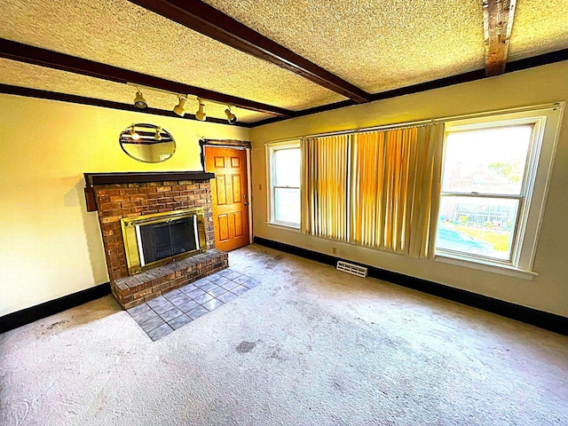 unfurnished living room with a brick fireplace, carpet flooring, beam ceiling, and visible vents