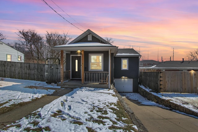 view of front of home featuring driveway, an attached garage, fence, and a porch