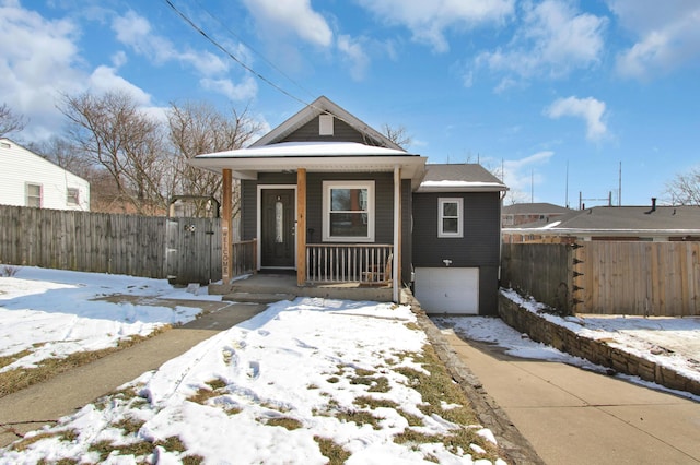 view of front of property with covered porch, driveway, fence, and a garage