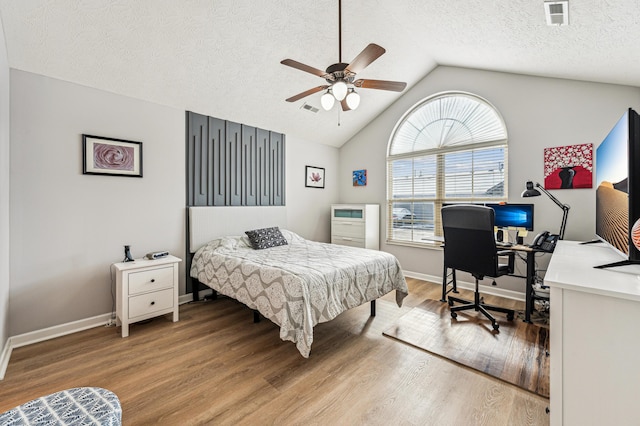 bedroom with a textured ceiling, lofted ceiling, ceiling fan, and wood-type flooring