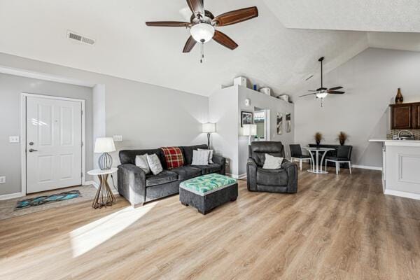 living room featuring lofted ceiling, ceiling fan, and wood-type flooring