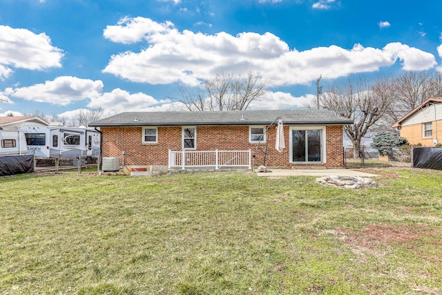 rear view of property with central air condition unit, brick siding, fence, and a lawn