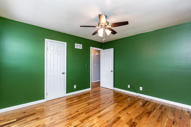 unfurnished bedroom featuring light wood finished floors, a ceiling fan, visible vents, and baseboards