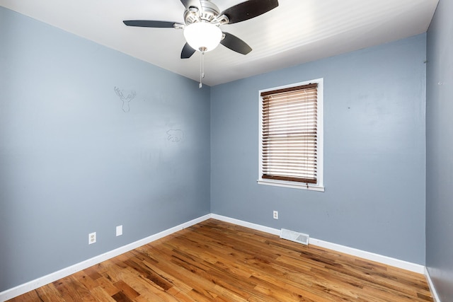 empty room featuring ceiling fan, wood finished floors, visible vents, and baseboards