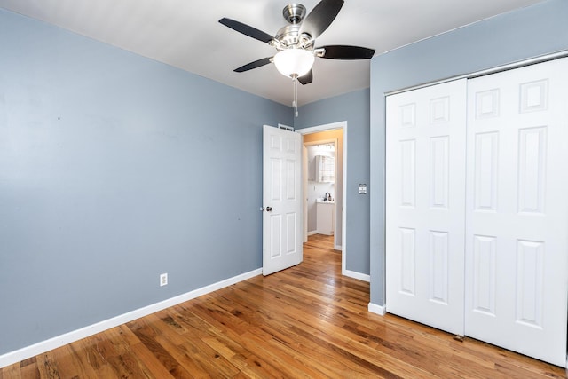 unfurnished bedroom with a closet, ceiling fan, light wood-style flooring, and baseboards