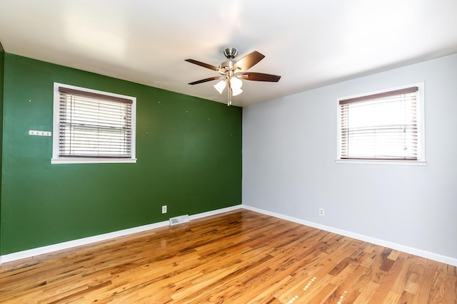 unfurnished room featuring a ceiling fan, visible vents, baseboards, and wood finished floors