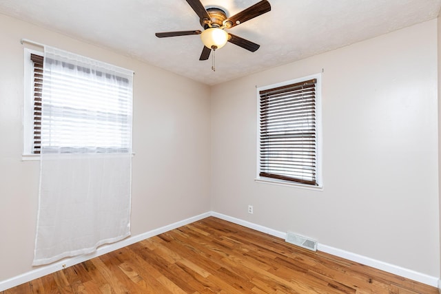 spare room featuring ceiling fan, light wood-type flooring, visible vents, and baseboards