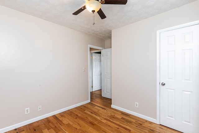 unfurnished bedroom featuring a textured ceiling, ceiling fan, light wood-style flooring, and baseboards