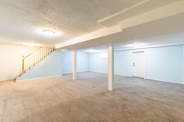 finished basement featuring carpet, stairs, baseboards, and a textured ceiling