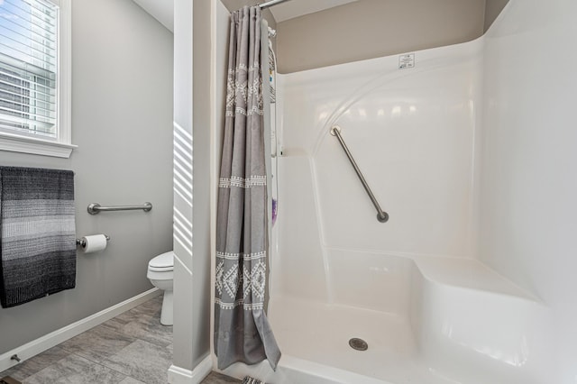 bathroom with a shower with shower curtain and toilet