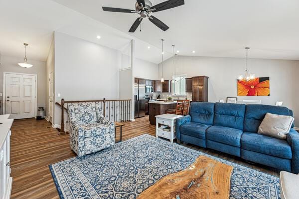 living room with ceiling fan with notable chandelier, high vaulted ceiling, and dark hardwood / wood-style floors