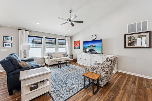 living room featuring high vaulted ceiling, dark hardwood / wood-style floors, and ceiling fan