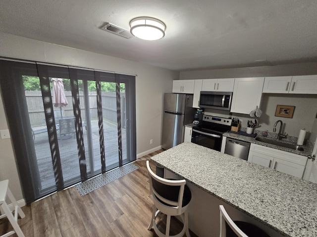7013 Curtis Way Unit 7013, Florence, KY 41042 - kitchen with stainless steel appliances, white cabinets, light stone counters, light wood-style flooring, and a kitchen bar