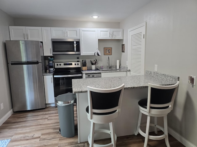 7013 Curtis Way Unit 7013, Florence, KY 41042 - kitchen with appliances with stainless steel finishes, a kitchen breakfast bar, a peninsula, light wood-style floors, and white cabinetry