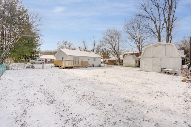 snow covered rear of property featuring a deck, an outdoor structure, and fence