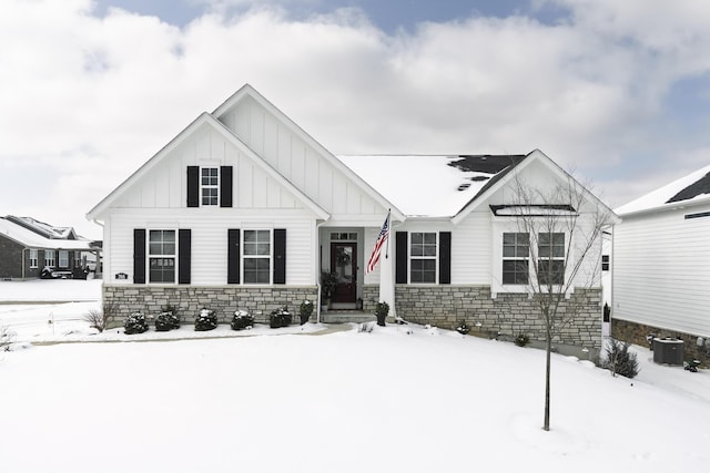 modern farmhouse with central AC unit, stone siding, and board and batten siding