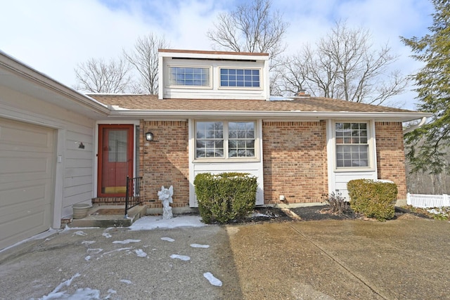 view of front of home with roof with shingles, an attached garage, and brick siding