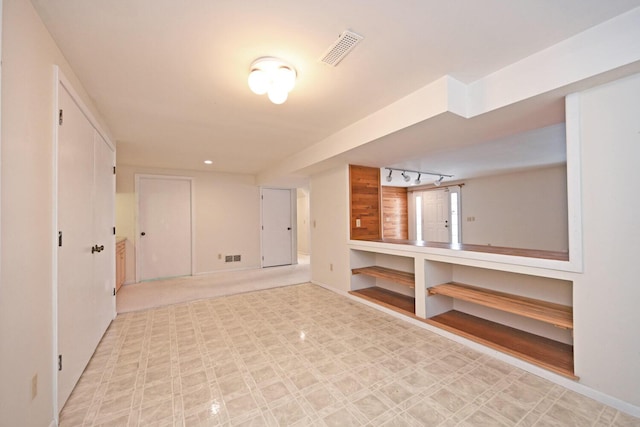 empty room featuring track lighting, visible vents, and light floors