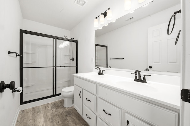 bathroom featuring toilet, hardwood / wood-style flooring, an enclosed shower, and vanity