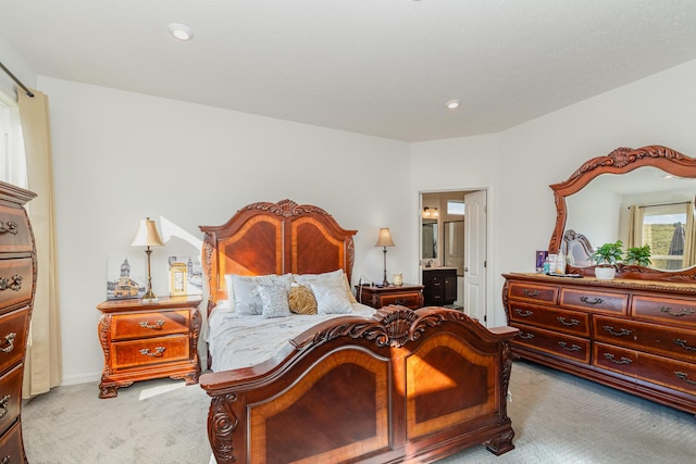 bedroom with recessed lighting, light colored carpet, and ensuite bath