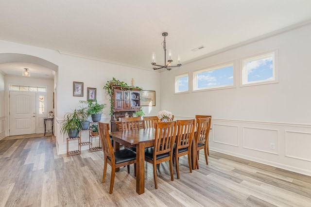 dining space featuring arched walkways, ornamental molding, visible vents, and a wealth of natural light