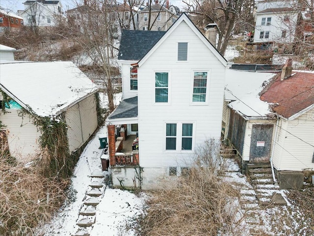 snow covered property with roof with shingles