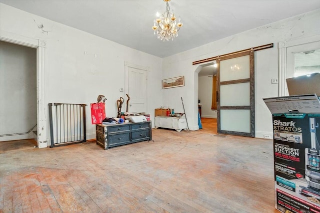 interior space with a chandelier, wood finished floors, baseboards, and a barn door