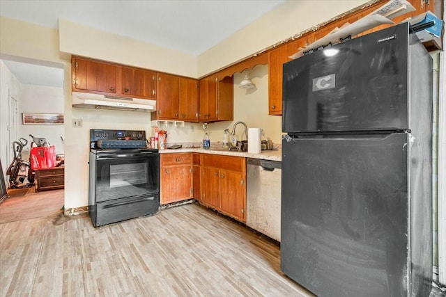 kitchen featuring light wood finished floors, light countertops, brown cabinetry, under cabinet range hood, and black appliances