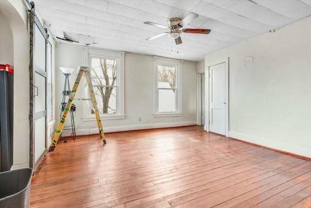 spare room with light wood-style floors, baseboards, and a barn door