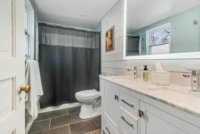 full bath featuring a sink, wooden walls, toilet, and double vanity