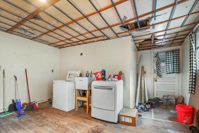 laundry area featuring a sink, washer and clothes dryer, wood finished floors, and a garage