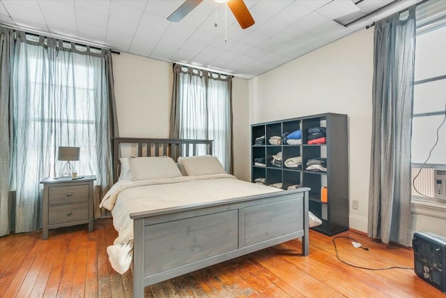 bedroom with ceiling fan, multiple windows, and wood finished floors