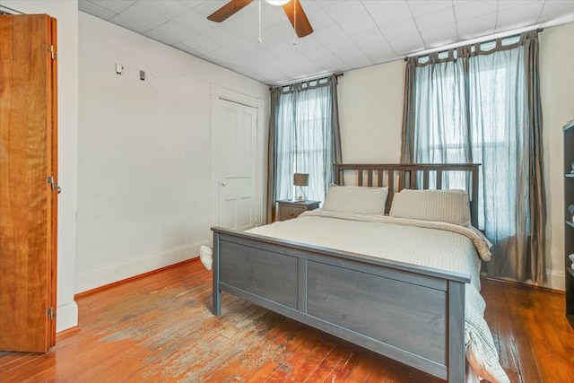 bedroom with a closet, multiple windows, baseboards, and wood finished floors