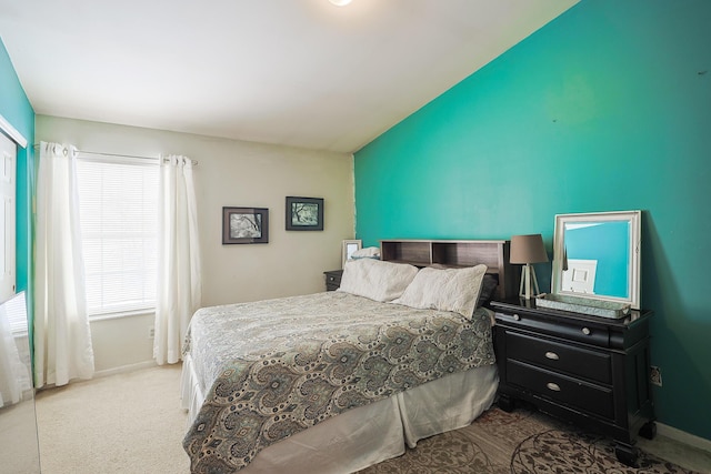 bedroom with baseboards, vaulted ceiling, and light colored carpet