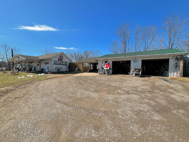 view of front facade with metal roof, a detached garage, and an outdoor structure