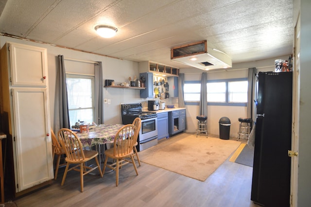 kitchen with light wood finished floors, stainless steel electric range oven, freestanding refrigerator, white cabinetry, and open shelves