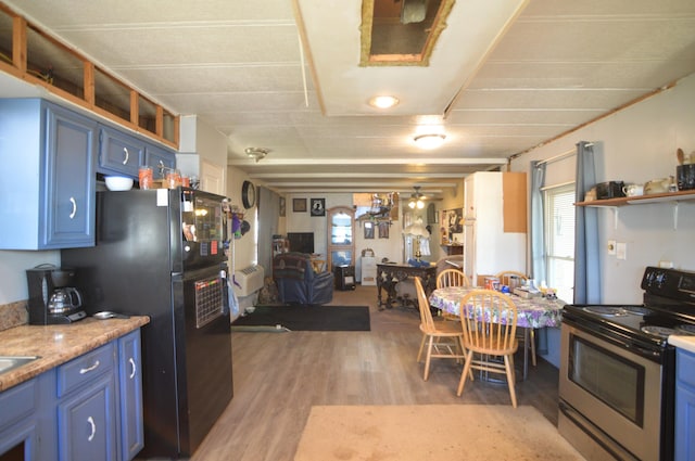 kitchen with light wood finished floors, open floor plan, blue cabinets, stainless steel range with electric cooktop, and open shelves