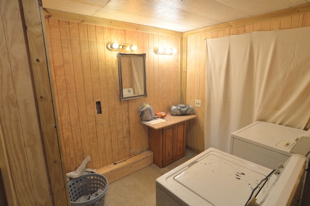 washroom with washing machine and dryer, laundry area, light colored carpet, and wood walls