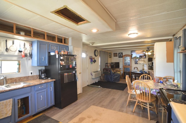 kitchen with blue cabinets, light countertops, a sink, and freestanding refrigerator