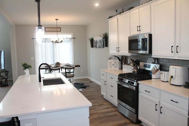 kitchen featuring appliances with stainless steel finishes, an island with sink, a sink, and white cabinets