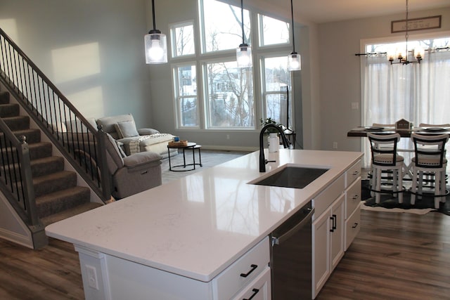 kitchen featuring an island with sink, a sink, white cabinetry, and pendant lighting