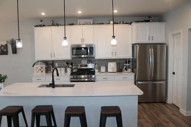 kitchen with appliances with stainless steel finishes, light countertops, decorative light fixtures, and a sink